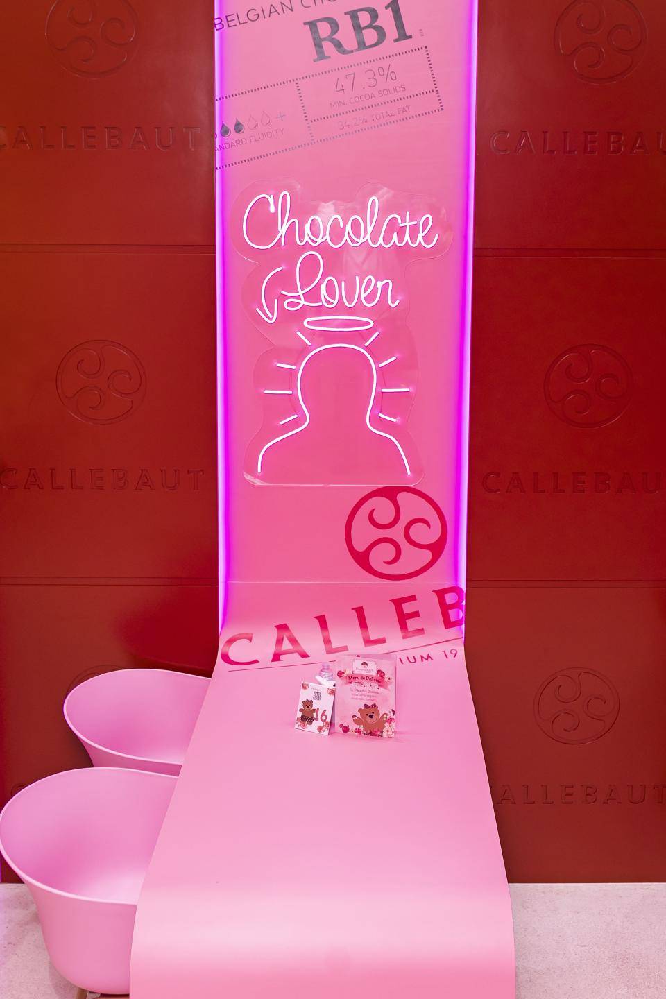 parede rosa e vermelha com neon formando um perfil de pessoa e com a seta para chocolate lover onde a pessoa pode se encaixar para tirar foto
