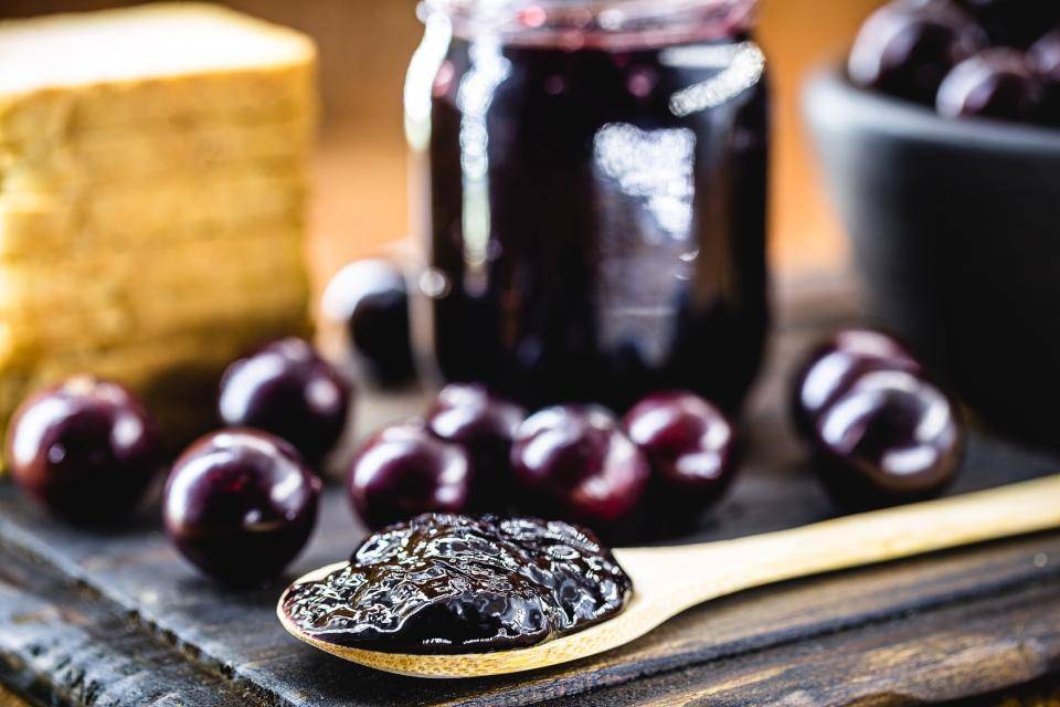 jabuticavas ao fundo e na frente uma colher com geleia em cima