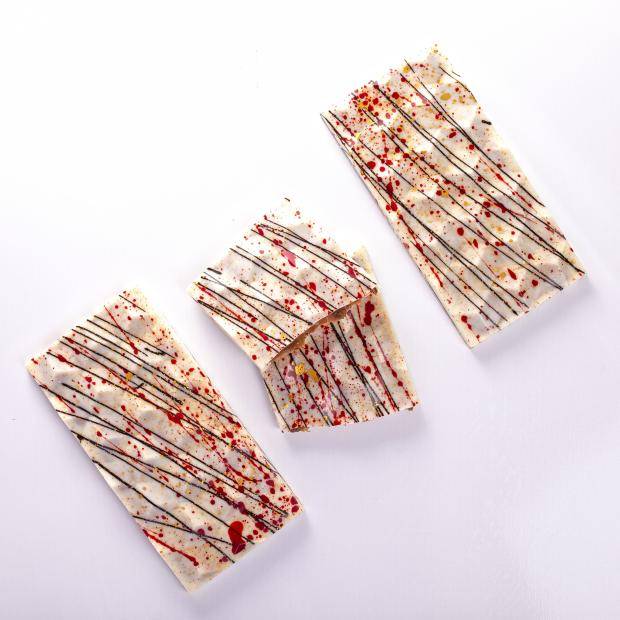 barras de chocolate suíco branca recheada com caramelo callebaut com decoração colorida em preto, vermelho e amarela