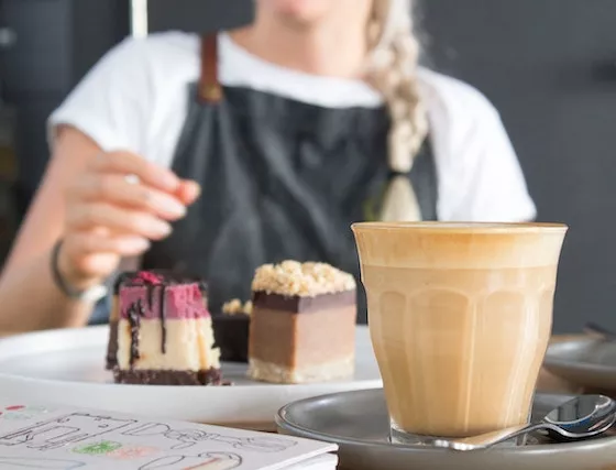 A server offers a tray with cakes and a drink