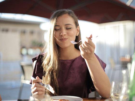A woman closes her eyes to better experience the bite she's just taken